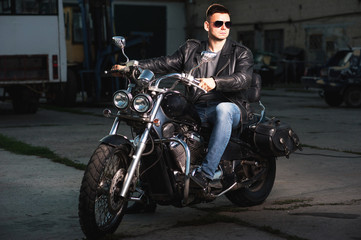 Fototapeta na wymiar Cute biker in leather jacket sits on a motorcycle