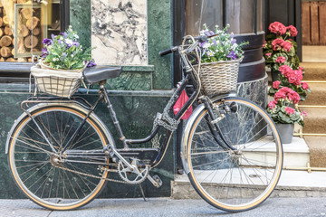 Fototapeta na wymiar Vintage bicycle with a basket in front and behind, in front of a store