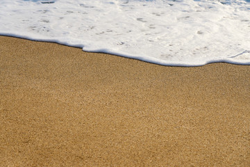                      Waves with foam hitting sand on the beach texture.          