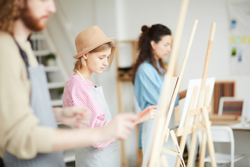 Fototapeta premium Young student of faculty of arts and her groupmates painting at lesson or course
