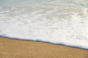                      Waves with foam hitting sand on the beach texture.          