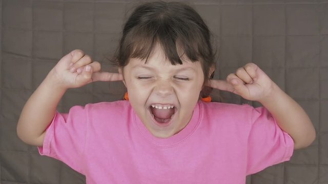 Screaming child covers ears. Cute little girl closes her ears and screams. Parents manipulation concept.