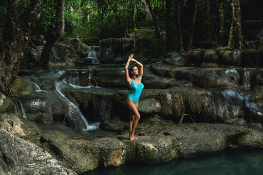 Young and sexy woman on the beautiful waterfall in the jungle