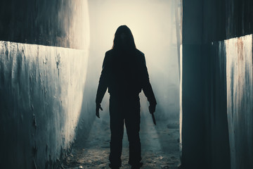 Silhouette of man maniac or killer or horror murderer with knife in hand in dark creepy and spooky corridor. Criminal robber or rapist concept in thriller atmosphere - obrazy, fototapety, plakaty