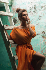 Naklejka premium Sensual woman wearing beautiful long dress on the old wooden ladder