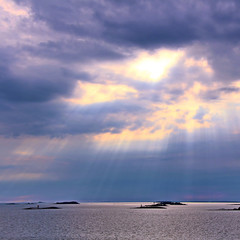 The sun behind the clouds with rays of light shining down on sea
