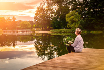 Sad lonely beautiful woman sitting on the pier.