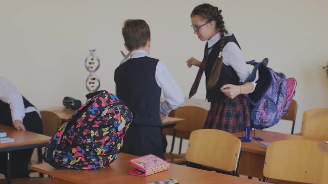 Schoolchildren in school uniform puts on a backpack to go home. Slow motion. High school students in the classroom