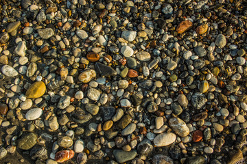 wet sea shore colorful waterfront stones background texture shot from above
