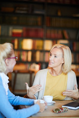 Confident blonde woman explaining what she thinks about the subject of her conversation with friend by cup of tea