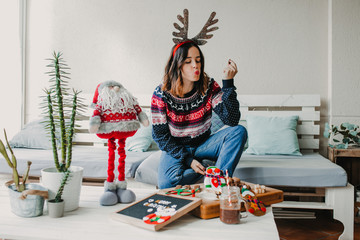 .Sweet and cheerful woman enjoying christmas at her home. Wearing christmas costume and eating tipical sweets. Lifestyle. Season photography.