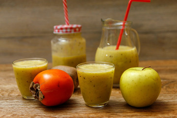 Freshly blended fruit smoothie with fresh fruits on wooden table with raw fruits