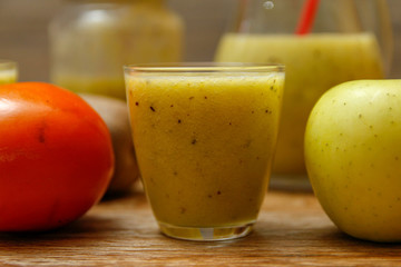 Freshly blended fruit smoothie with fresh fruits on wooden table with raw fruits