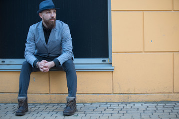 stylish man with a beard and a hat near the desirable wall