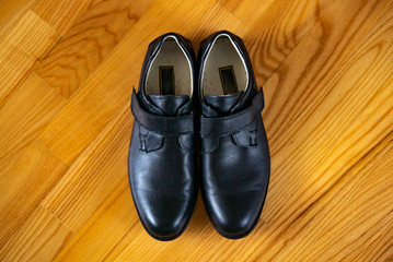 New classic leather shoes on a wooden background. Top view of boys shoes in the centre on wooden surface.