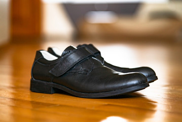 Black school shoes for a boy on a wooden surface. Contemporary design, daily wear men's black shoes over the wooden background.