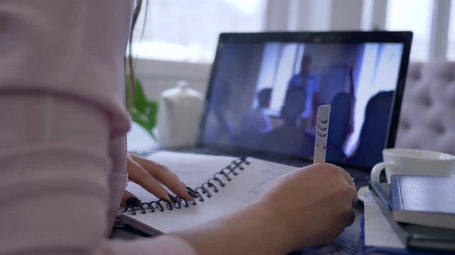 e-learn, student female using laptop computer for video education to learn from online teaching and remote working discussion making notes in notebook, close-up