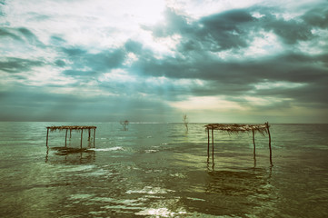 Fototapeta na wymiar Rustic wooden palapas stand empty in shallow waters under the tropical skies of Bahia, Brazil