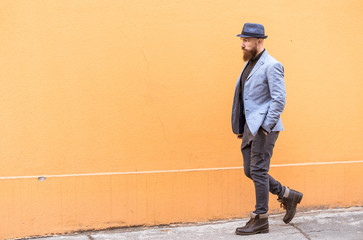 stylish man with a beard and a hat near the desirable wall