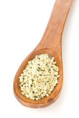 Heap of raw, organic hemp seeds on wooden spoon over white
