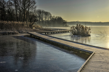 Wooden walkway covered with hoarfrost zigzagging across  lake Kralingse Plas in Rotterdam, The...