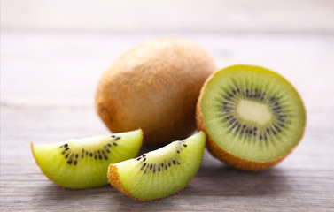 Fresh kiwi fruit and slices of kiwi on grey wooden background