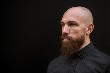 bald man with a beard in a black shirt on a dark background