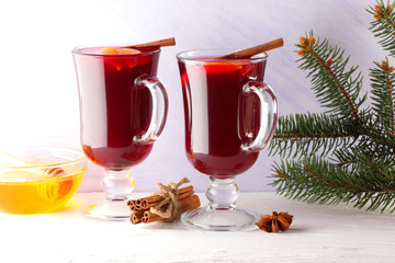Mulled wine on white background. Christmas mulled wine, cinnamon sticks, anise and honey. Alcoholic drink of wine, fruit and honey. Festive drink and Christmas tree branches