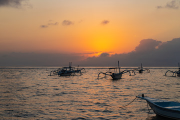 Beautiful sunrise at Sanur Beach, Bali. Traditional fishing boat on seashore at colorful sunrise. Indonesia.