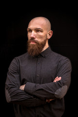 bald man with a beard in a black shirt on a dark background