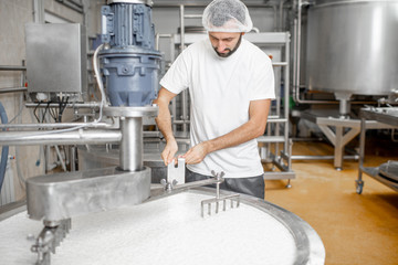 Man mixing milk in the stainless tank during the fermentation process at the cheese manufacturing