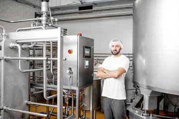 Portrait of a handsome worker operating pasteurizer using the control panel at the cheese or milk...