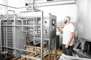 Worker operating pasteurizer using the control panel at the cheese or milk manufacturing - obrazy, fototapety, plakaty