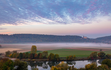 Fototapeta na wymiar Morning view on castle Guttenberg, Haßmersheim, and river Neckar with fog in the fields from castle Horneck, Gundelsheim, Germany