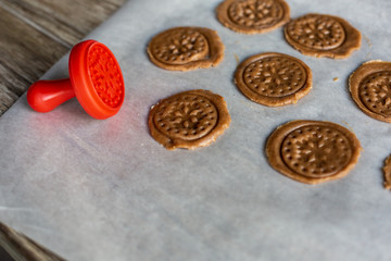 Raw gingerbread cookies from the dough on the parchment.