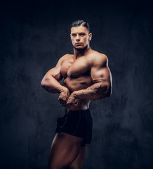 Fototapeta na wymiar A handsome athletic man with muscular body standing in bodybuilder competitive pose