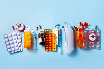 Healthcare concept - pills and medical instruments row on blue