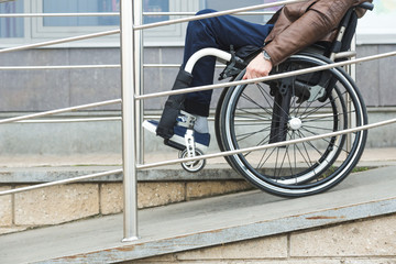 Man in a wheelchair use a wheelchair ramp.