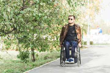 A young man in a wheelchair rides along the park road.