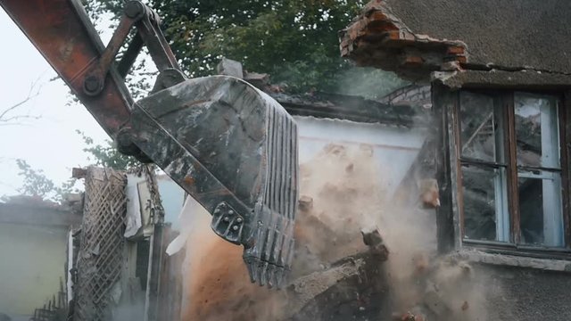 The old by backhoe excavate the stones and bricks broken fall down old abandoned empty busted shattered house bulding destroyed by backhole destroy the walls doors windows and ceiling near.