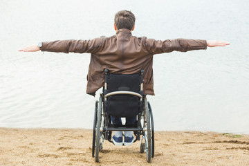 Young man sitting in a wheelchair by the lake.