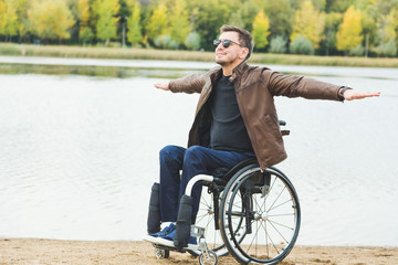 Young man sitting in a wheelchair by the lake.