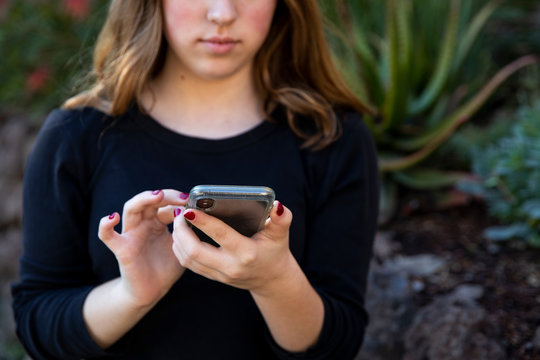 Teenage girl holding smart phone outdoors