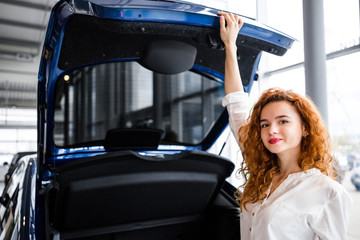 Red-haired girl opened the trunk of the car