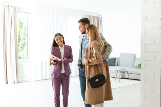 Female real estate agent working with couple in room
