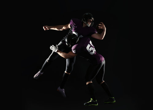 Men in uniform playing American football on dark background