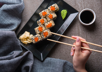 Eating sushi roll on black plate. Overhead view