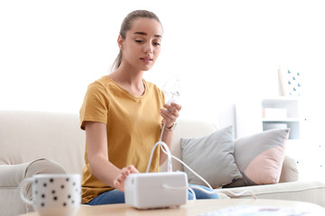 Young woman using asthma machine at home. Health care