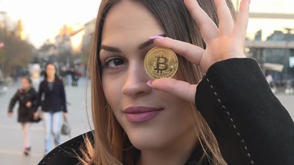 Bitcoin, Elegant young woman holding a bitcoin - Powered by Adobe