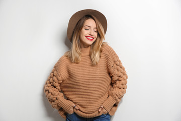 Beautiful young woman in warm sweater with hat on white background - Powered by Adobe